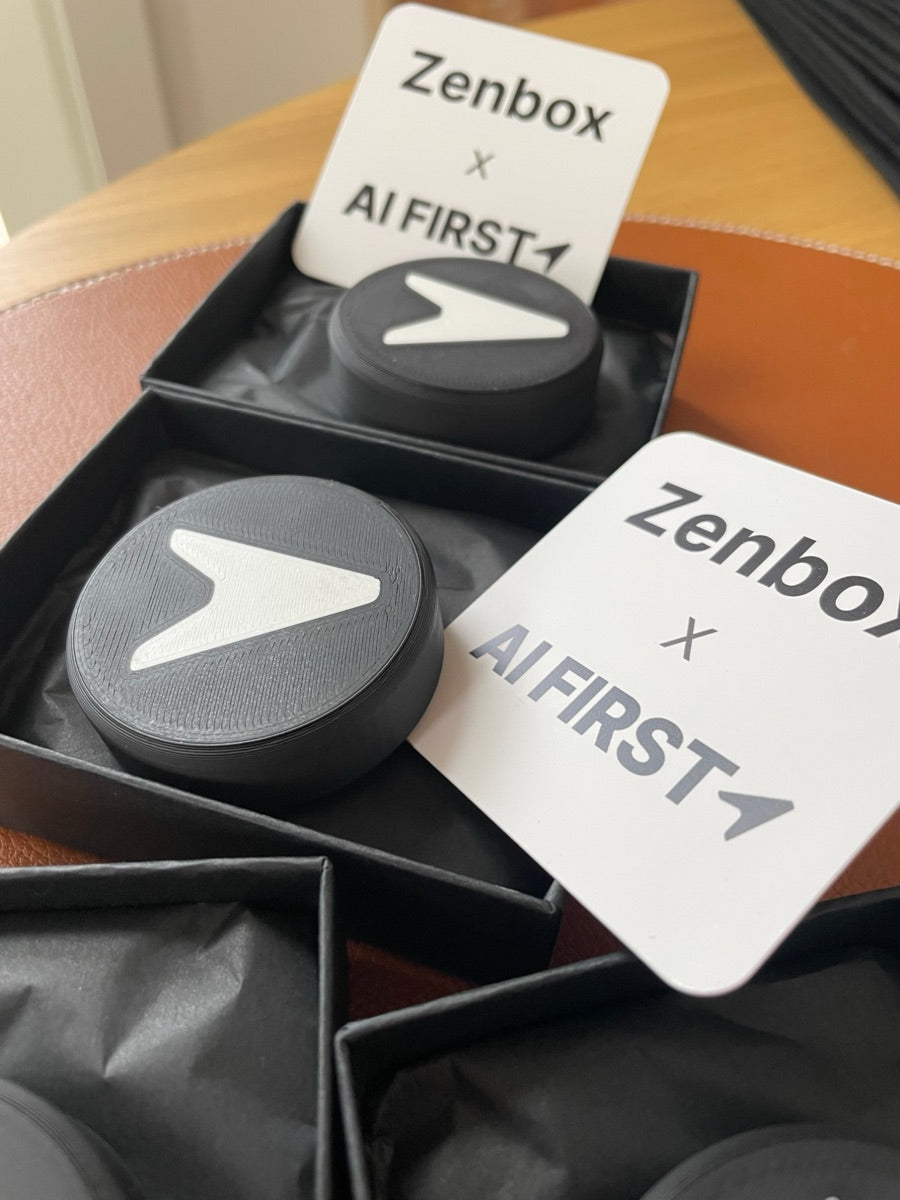 Schwarze Zenbox mit AI-First-Logo in einer Geschenkbox, daneben eine Karte mit Zenbox x AI First